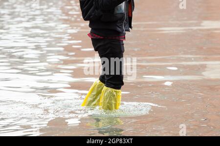 Close Up di gambe con scarponi dovuta all'acqua alta. Questo flusso si verifica quando vi è alta marea a Venezia, Italia. Foto Stock