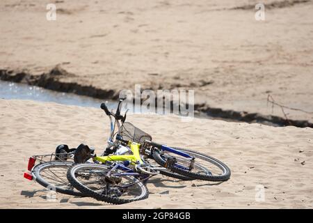 Due vecchie biciclette parcheggiate sulla spiaggia di sabbia. Foto Stock