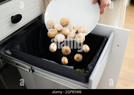 Gettando via cibo residuo nel cestino o nel cestino della spazzatura Foto Stock