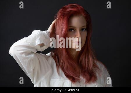 Basso ritratto chiave di bella giovane donna rossa con mano in capelli. Orizzontalmente. Foto Stock