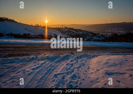 Strada con neve in inverno vigneto paesaggio e retroilluminato Foto Stock