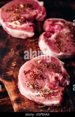Materie lombo di maiale bistecche con diverse spezie rustico tagliere Foto Stock