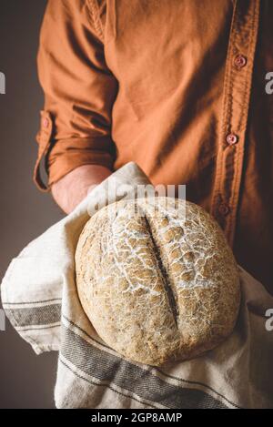 Baker contiene una pagnotta di pane di segale appena sfornato Foto Stock