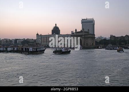 Taj Mahal Hotel, Gateway of India e barche turistiche in acqua del Mar Arabico al tramonto a Mumbai, India Foto Stock