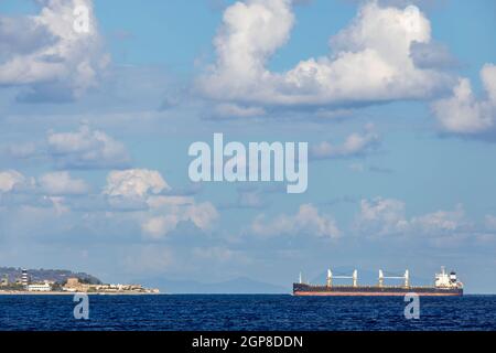 Nave da carico vicino Faro di Capo Peloro a Punta del Faro sullo stretto di Messina, promontorio più a nord-est della Sicilia, Italia Foto Stock