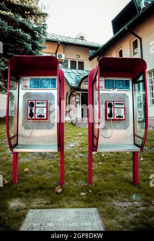 Due vecchie cabine telefoniche rosse l'una accanto all'altra di fronte ad un ufficio postale Foto Stock