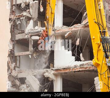 Demolizione di un edificio di nuova costruzione, utilizzando un escavatore speciale-cacciatorpediniere. Completare altamente meccanizzata di demolizione di strutture edili. Foto Stock