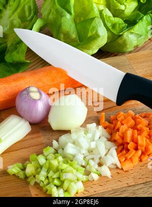 Coltello in ceramica con il soffritto sul tagliere di legno Foto Stock