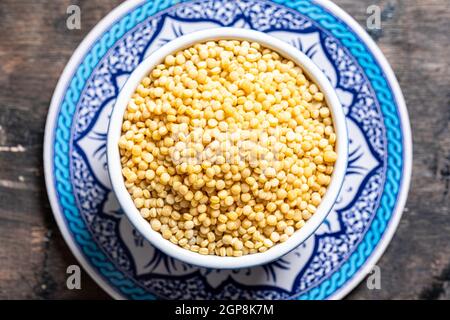 Primo piano del ptitim secco. Pasta tostato pittim (petit plomb o couscous israeliano) su sfondo di legno Foto Stock