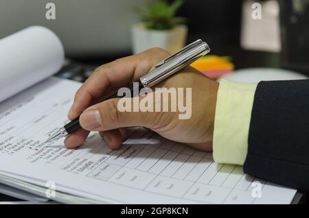 Mano con penna scrivere i documenti dell'applicazione sulla scrivania. Foto Stock