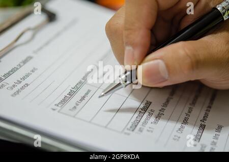 Mano con penna scrivere i documenti dell'applicazione sulla scrivania. Foto Stock
