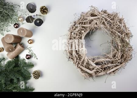 Corona di legno pallido e decorazione come braci fuoco, candele e baubles per le vacanze di Natale e di Avvento su un tavolo bianco, alto angolo di vista da abov Foto Stock