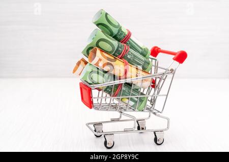 Carrello spesa pieno del rotolo di banconote in euro Foto Stock