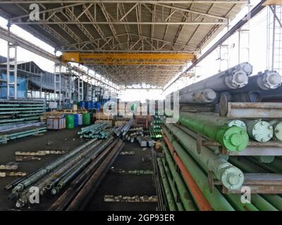 Stoccaggio di tubi per l'industria petrolifera. Motori elettrici sommersi. Barili con reagente. Foto Stock