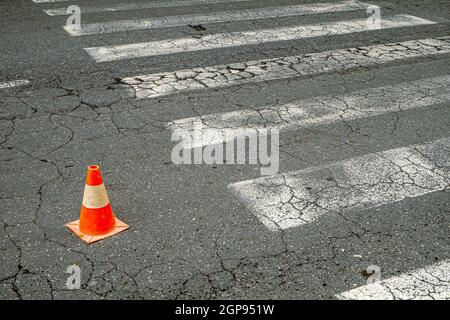 Cono di traffico di due colori situato in una strada della città ruvida Foto Stock