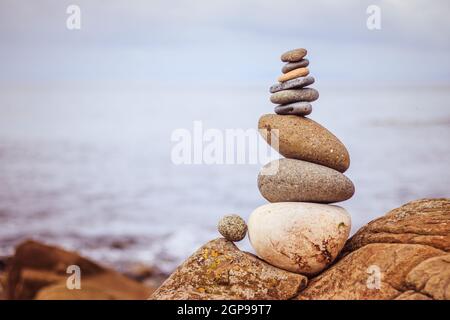 Vicino la foto di una pietra cairn all'esterno. Il mare in sfondo sfocato Foto Stock