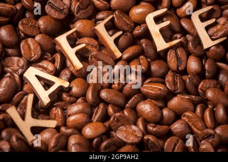 Visualizzazione completa dei chicchi di caffè tostati con lettere in legno sulla parte superiore che rappresentano la parola caffè. Foto Stock