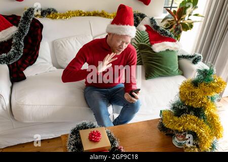 Albino african american uomo che indossa santa Hat fare videochiamata con decorazioni di natale Foto Stock