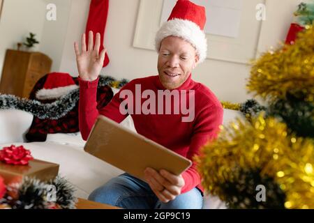 Albino african american uomo che indossa santa Hat fare videochiamata con decorazioni di natale Foto Stock