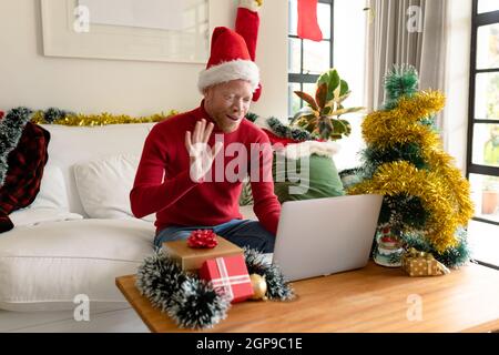 Albino african american uomo che indossa santa Hat fare videochiamata con decorazioni di natale Foto Stock