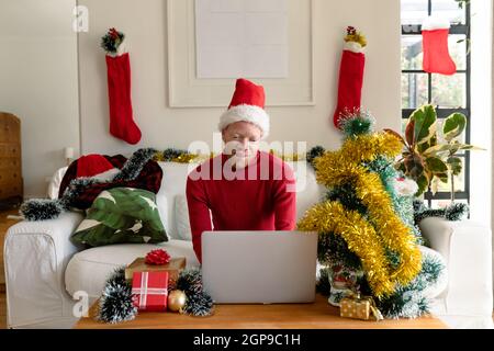 Albino african american uomo che indossa santa Hat fare videochiamata con decorazioni di natale Foto Stock