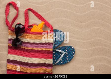 Borsa da spiaggia con protezione solare, flip flop, occhiali da sole. Vacanze estate sfondo Foto Stock