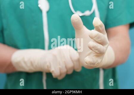 Il medico si prepara per l'intervento chirurgico e indossa guanti di gomma per l'igiene ospedaliera close-up Foto Stock