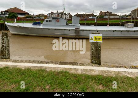 Vista di una grande barca arenarsi a bassa marea al terrapieno del porto fluviale presso il villaggio storico di segala, East Sussex Foto Stock