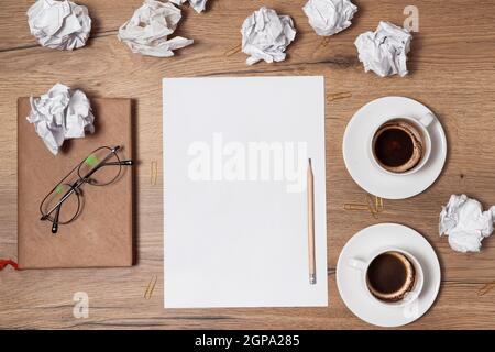 Carta sminuzzata sparsa, tazze vuote di caffè sul tavolo di un lavoratore creativo. Crisi creativa. Concetto di stress, problemi di salute mentale e mancanza di me Foto Stock