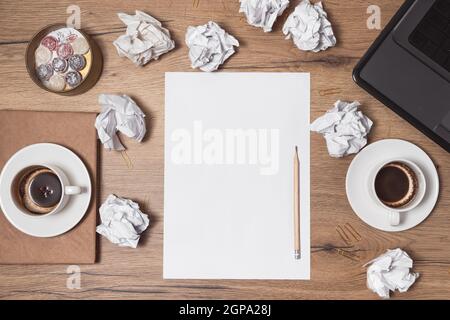 Carta sminuzzata sparsa, tazze vuote di caffè sul tavolo di un lavoratore creativo. Crisi creativa. Concetto di stress, problemi di salute mentale e mancanza di me Foto Stock