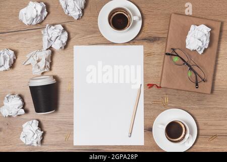 Carta sminuzzata sparsa, tazze vuote di caffè sul tavolo di un lavoratore creativo. Crisi creativa. Concetto di stress, problemi di salute mentale e mancanza di me Foto Stock