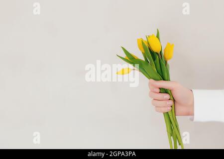 Mazzo con fiori di tulipano gialli su fondo grigio in cemento. Concetto di biglietto d'auguri per Pasqua, Festa della mamma, Internazionale delle donne Foto Stock