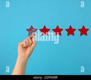 vai a segno cinque stelle rosse e una mano femminile si disegna su sfondo blu, alto rating Foto Stock