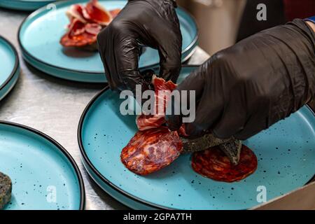 Lo chef stappata lo jamon su un piatto di antipasti. Concetto di arte della placcatura Foto Stock