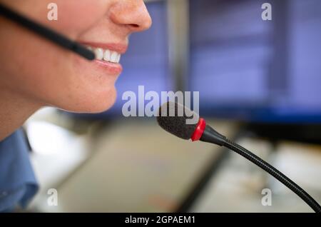 Il dipendente del call center comunica tramite telefono utilizzando un microfono esterno per una migliore ergonomia e sounf Foto Stock