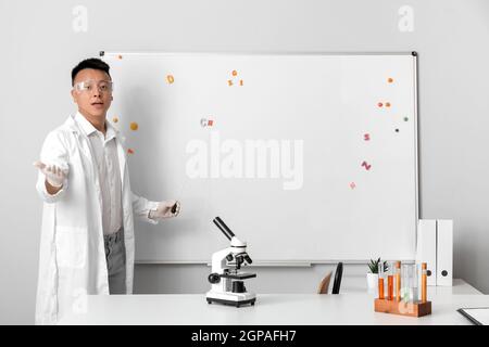 Insegnante asiatico che conduce la lezione di chimica Foto Stock