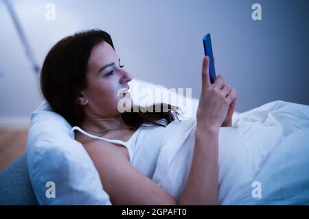 Insonnia Casa da sola utilizzando il telefono a tarda notte Foto Stock