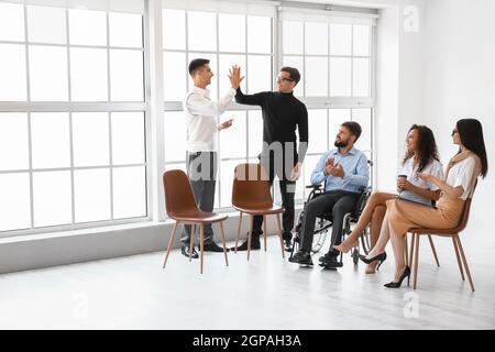 Colleghi maschi che si danno l'un l'altro alto cinque durante la riunione in ufficio Foto Stock