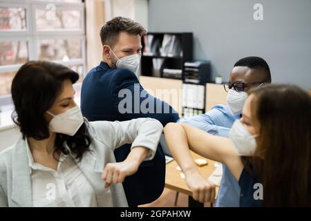 Uomini d'affari gomito Bump indossare maschera Covid viso Foto Stock