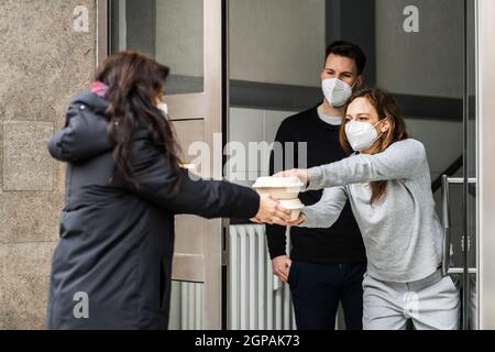 Vicino che dà aiuto di cibo di salvataggio in maschera di faccia Foto Stock