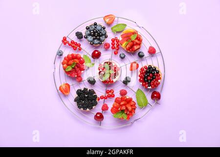 Composizione con gustosi tartine di bacche su sfondo viola Foto Stock