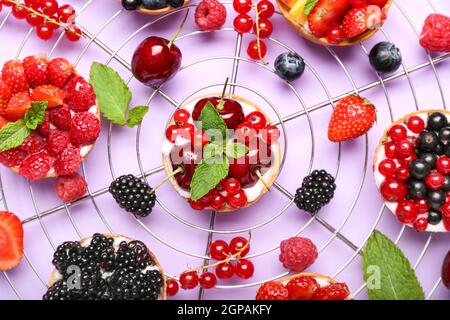 Composizione con gustosi tartine di bacche su sfondo viola Foto Stock
