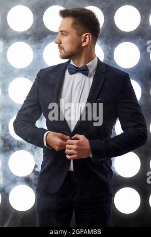 bell'uomo elegante in tuxedo che posa sul palco. vita notturna Foto Stock
