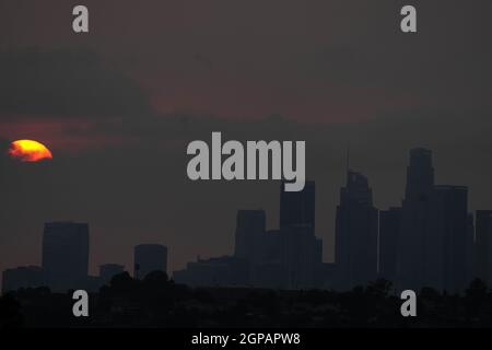 Il sole tramonta sullo skyline del centro in cieli oscurati da incendi selvatici, martedì 28 settembre 2021, a Los Angeles. Foto Stock