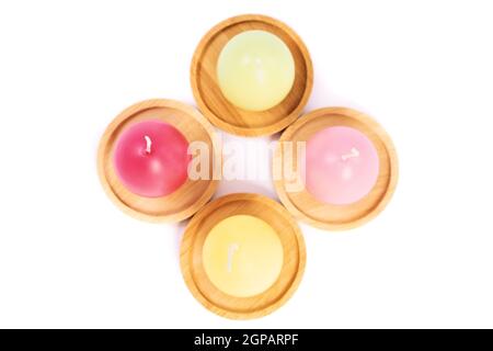 Vista dall'alto di candele a forma di uovo in colori pastello su piattini di legno, isolate su sfondo bianco. Divertente e colorato concetto di festa di Pasqua. Pasqua d Foto Stock