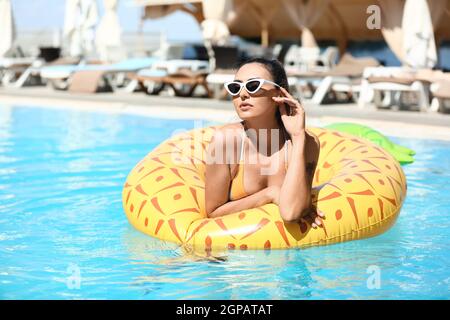 Giovane donna con anello gonfiabile in piscina Foto Stock