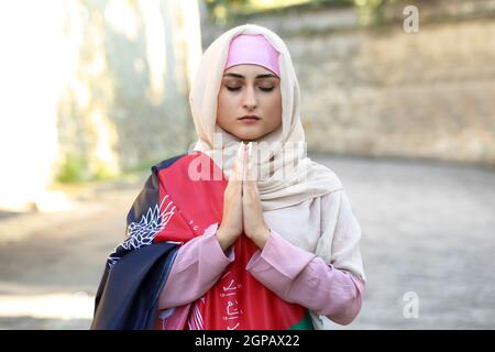 Donna musulmana in preghiera con bandiera dell'Afghanistan sulla strada della città Foto Stock