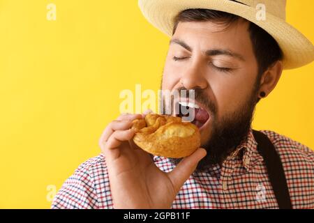 Bell'uomo in abiti tradizionali tedeschi e con pretzel su sfondo colorato Foto Stock