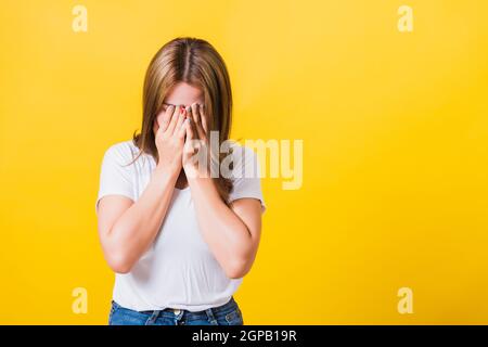 Asiatico Thai ritratto bella giovane donna in depressione cattivo umore il suo grido faccia vicino a mani, ha chiuso il suo volto a causa di essere imbarazzato studio s. Foto Stock