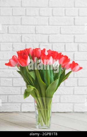 Tulipani rosa in vaso di vetro su sfondo bianco muro di mattoni Foto Stock